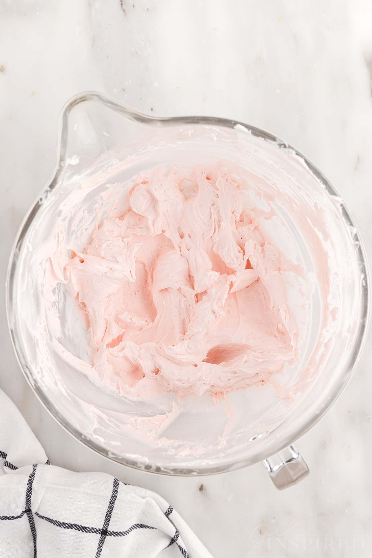 Pink strawberry frosting fluffy in mixing bowl.