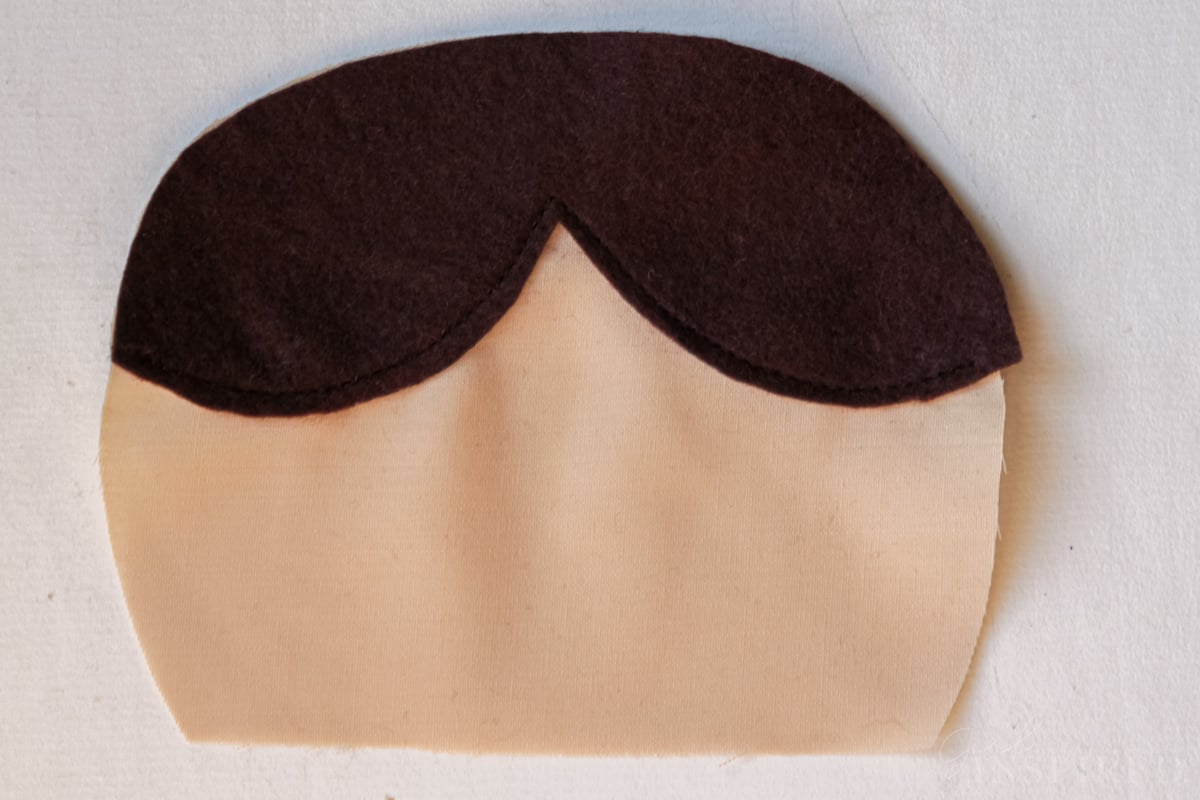 Felt piece placed over head shape to make bangs on cloth doll.