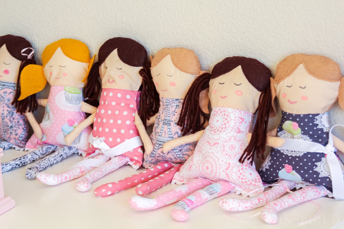 Six completed rag dolls sitting in a row, all with different hair and fabric clothing combos.
