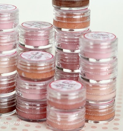 small plastic pots with various shades of pink and mauve lip gloss inside, stacked on one another