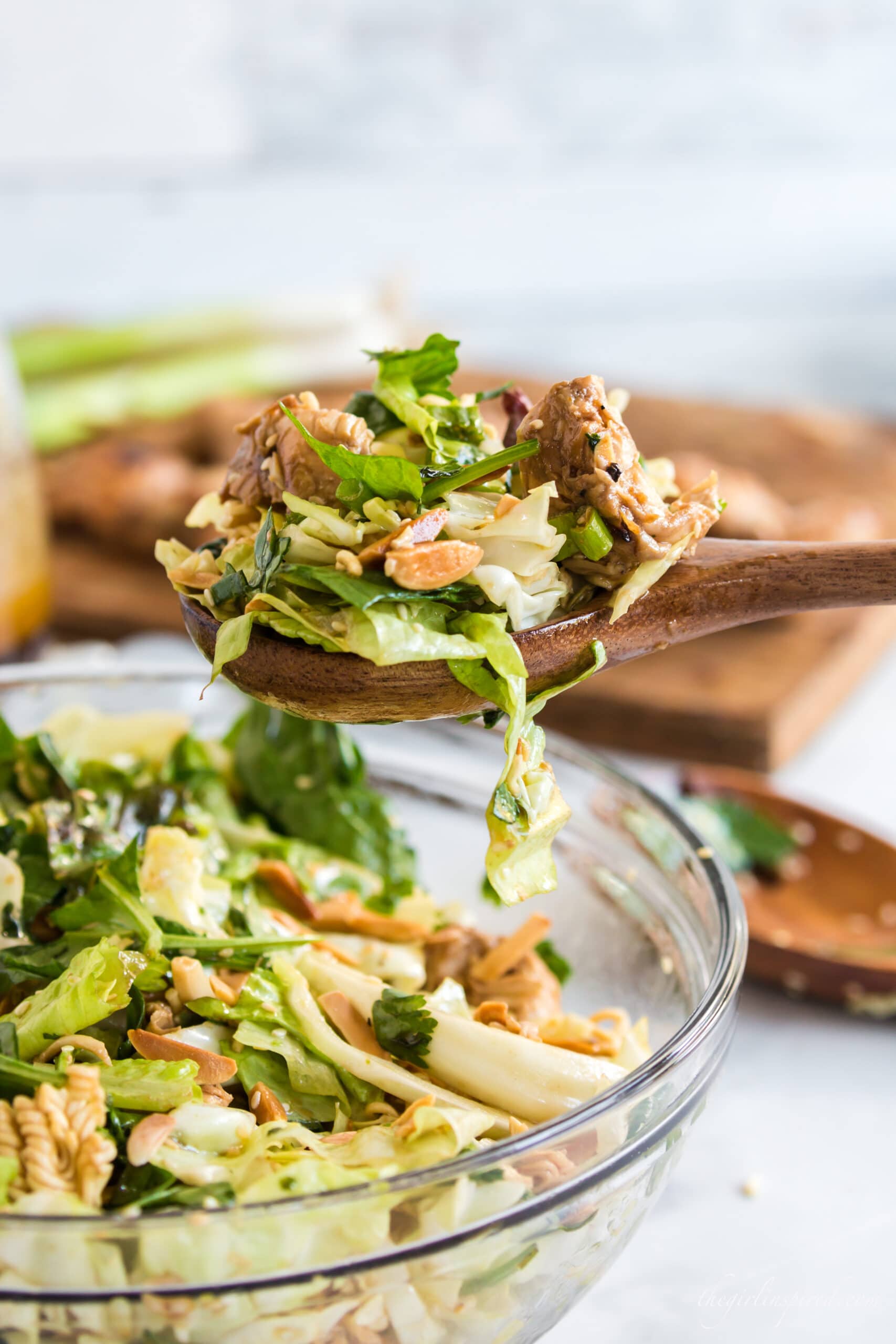 wooden spoonful of Chinese chicken salad scooping from glass salad bowl