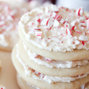 stacked sugar cookies with white frosting and pieces of candy cane on top