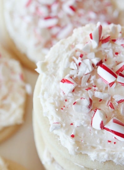 overhead of stacked sugar cookies with white frosting and pieces of candy cane on top