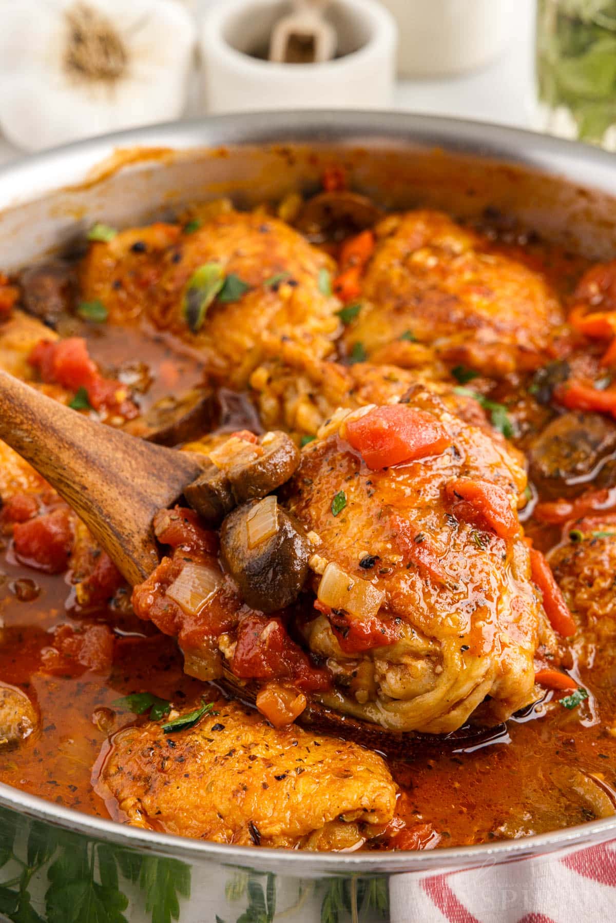 Spatula lifting the chicken from the chicken cacciatore pan.