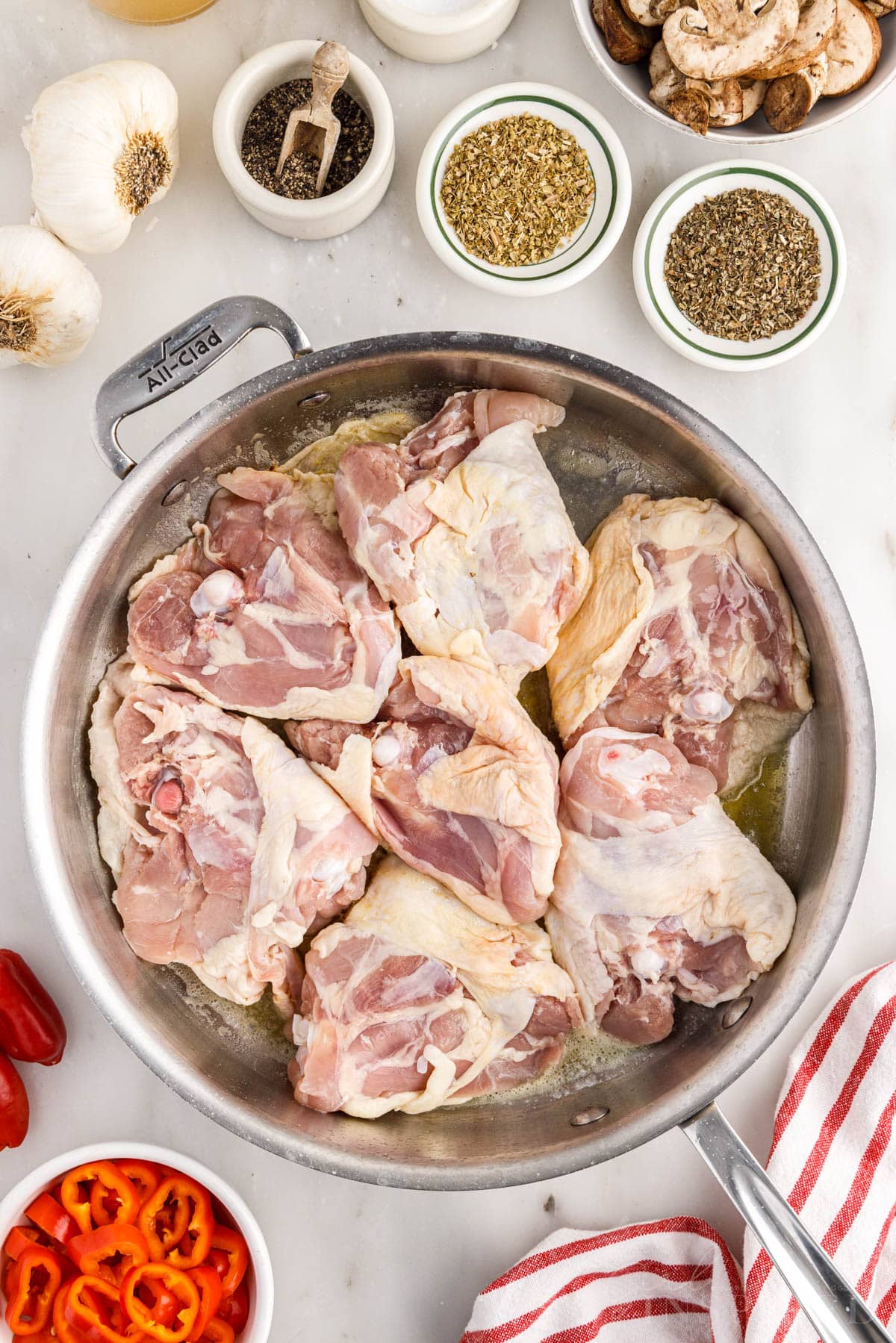 Chicken thighs cooking in large skillet.