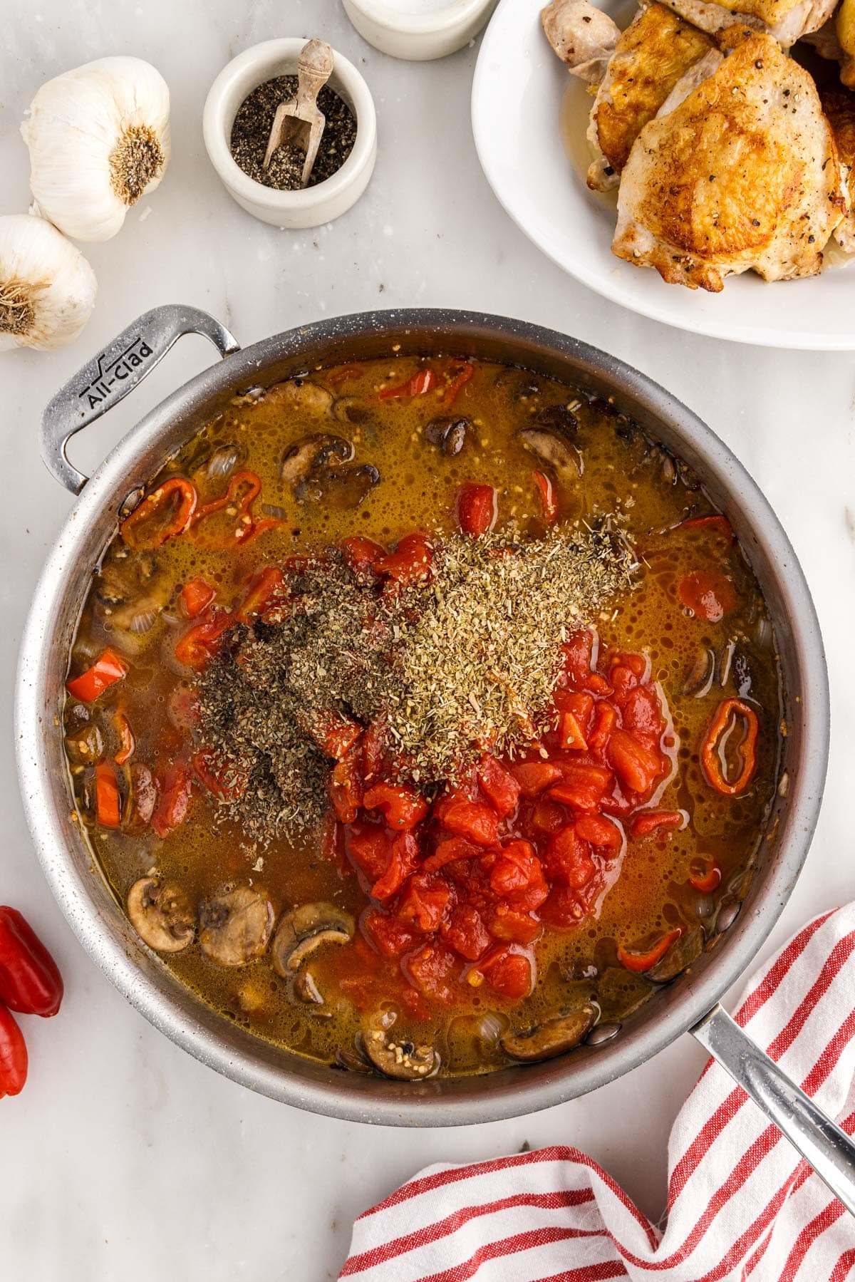 Diced tomatoes, basil, oregano, and chicken broth added to the skillet.