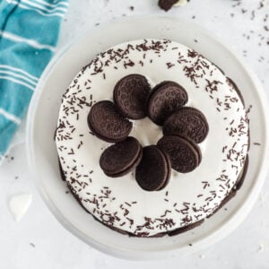 overhead photo of oreos and chocolate sprinkles on ice cream cake on white plate with aqua linen
