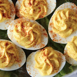 overhead of deviled eggs with swirled filling and sprinkled paprika on a bed of lettuce