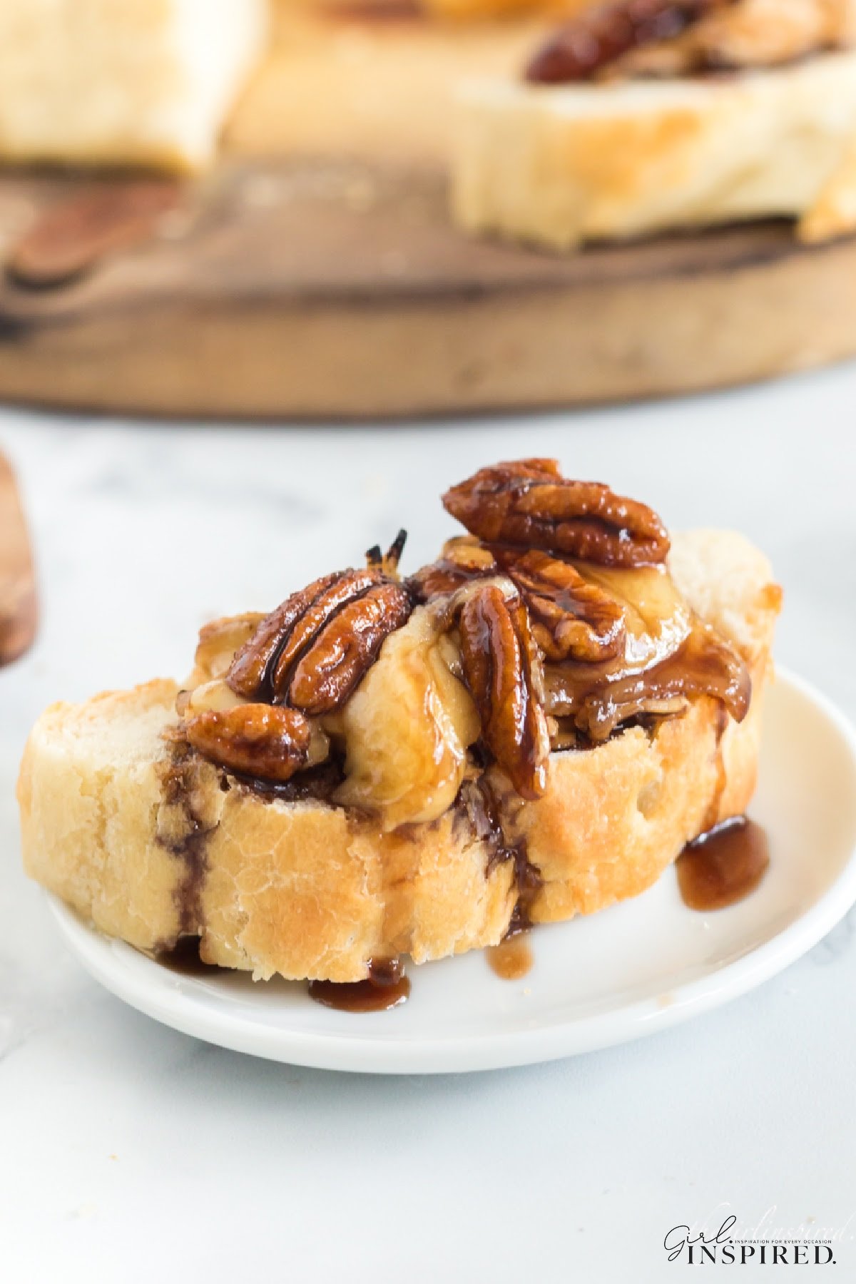 Brown sugar baked brie with brown sugar pecans on top of a small piece of bread.