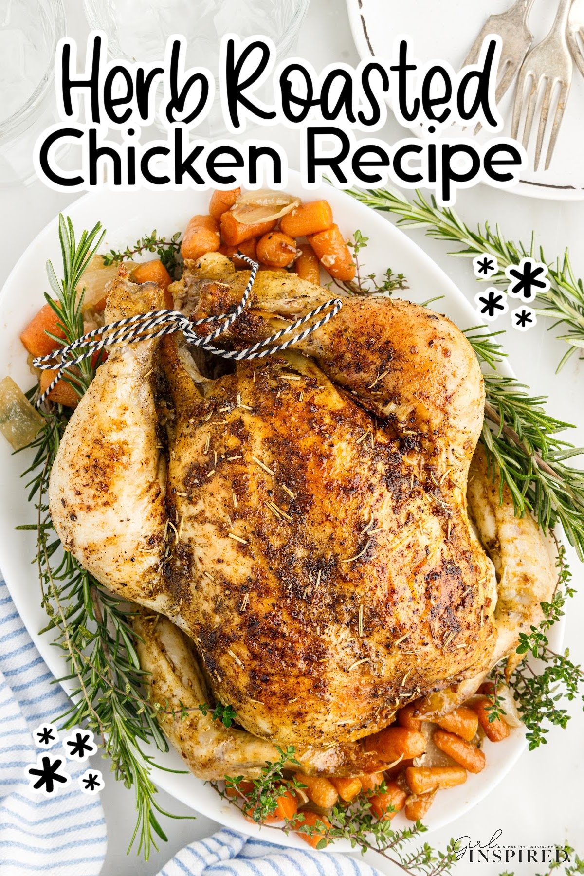 Whole herb roasted chicken on a serving tray with carrots, onions, and rosemary sprigs.