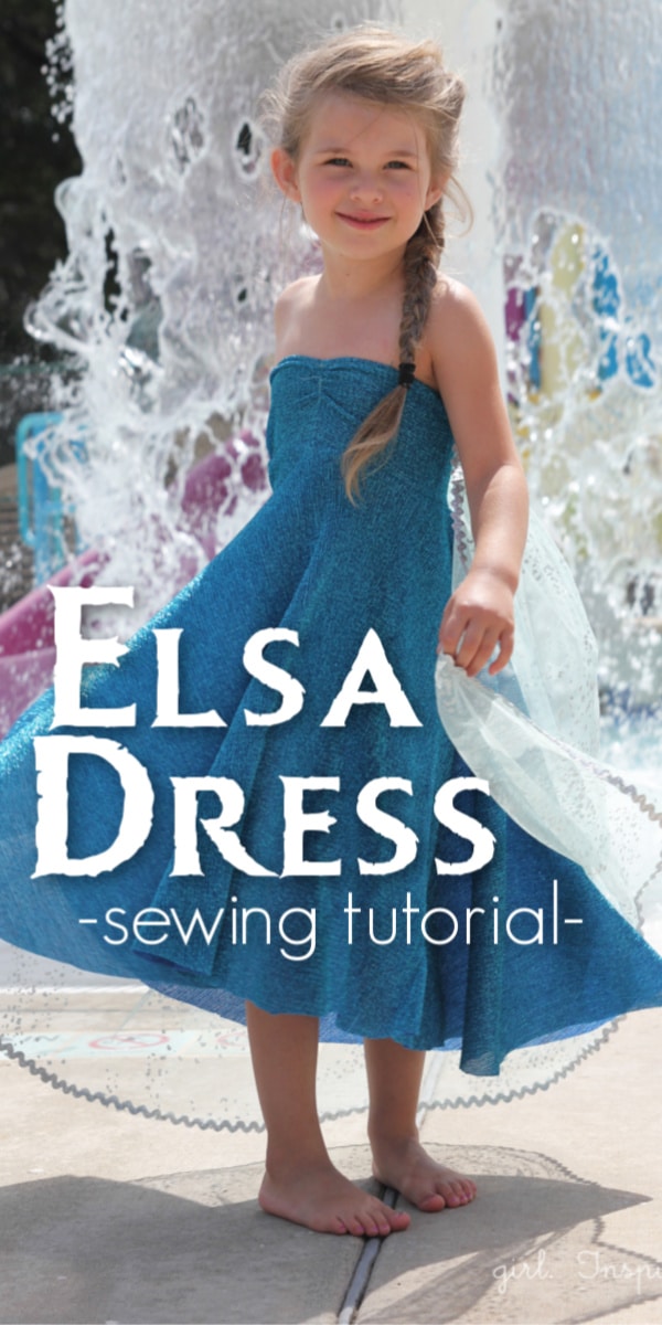 girl in blue dress with water spraying up behind her