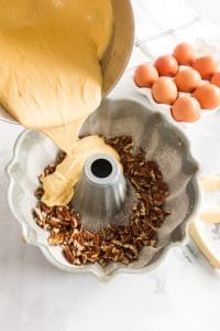 batter pouring into prepared bundt pan over nuts