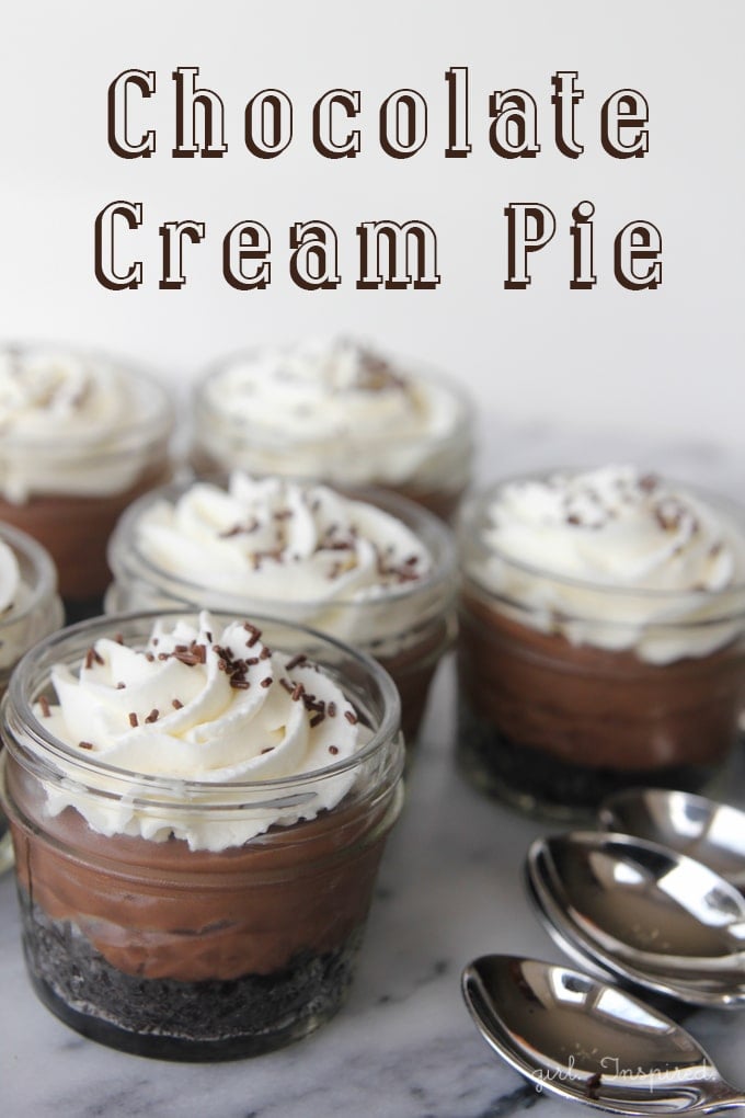 Chocolate crust, chocolate custard, and whipped cream layered in small mason jars with silver spoons and a text overlay.