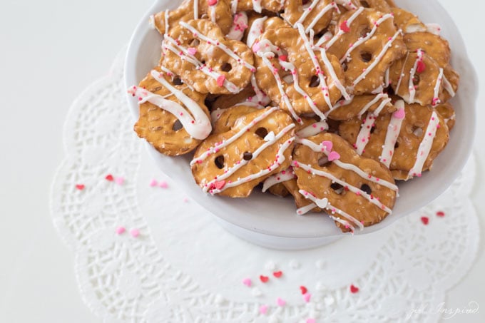 flat pretzel chips with white candy coating drizzled over them and pink and red heart sprinkles