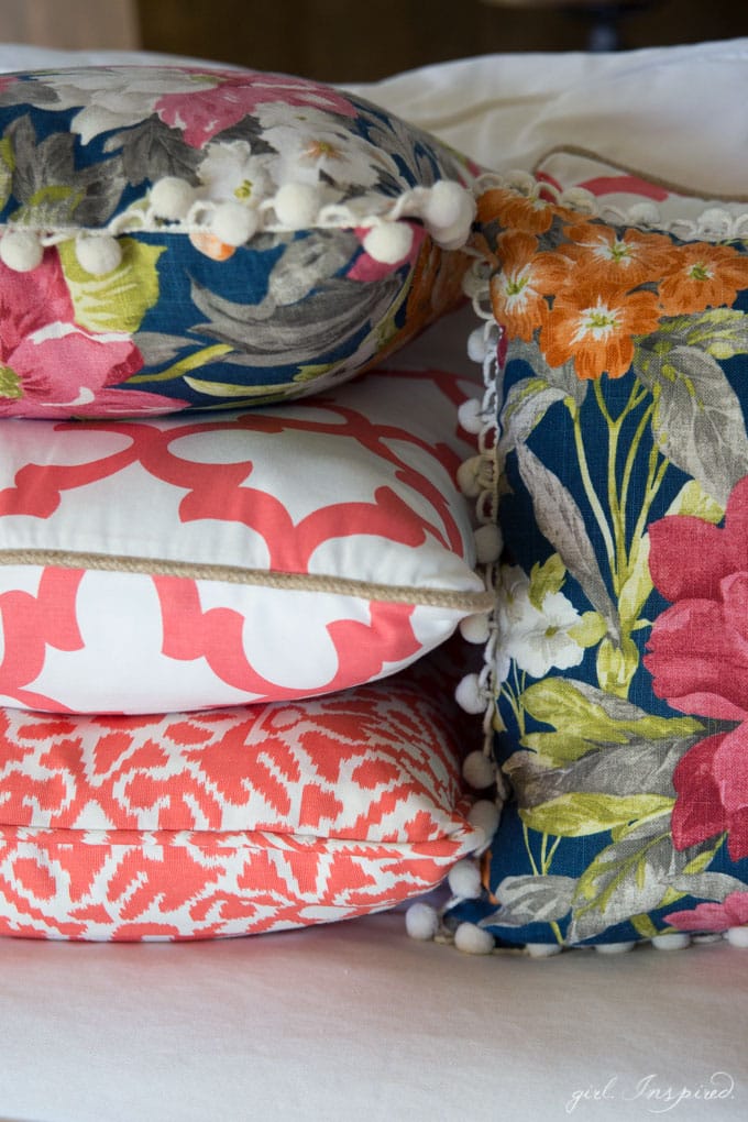 stacked coral, white and blue floral pillows on white couch