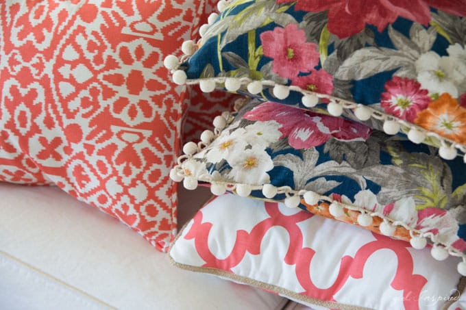 stacked blue floral and coral/white pillows on white couch