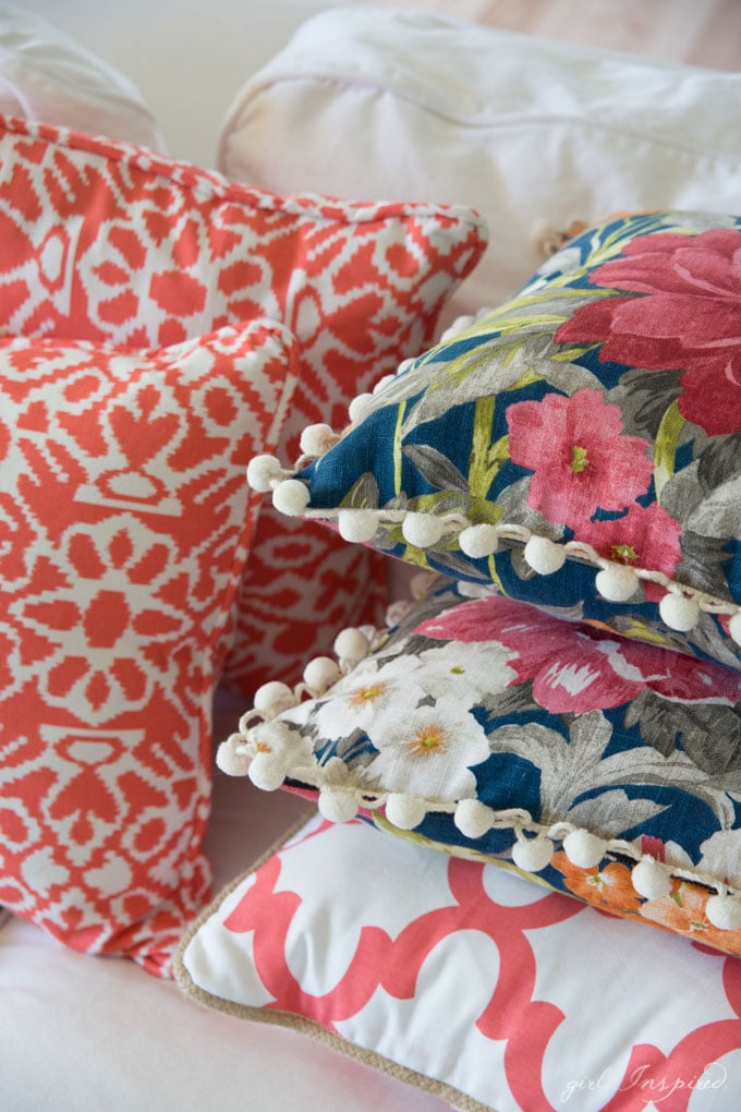 stacked blue floral and coral/white pillows on white couch