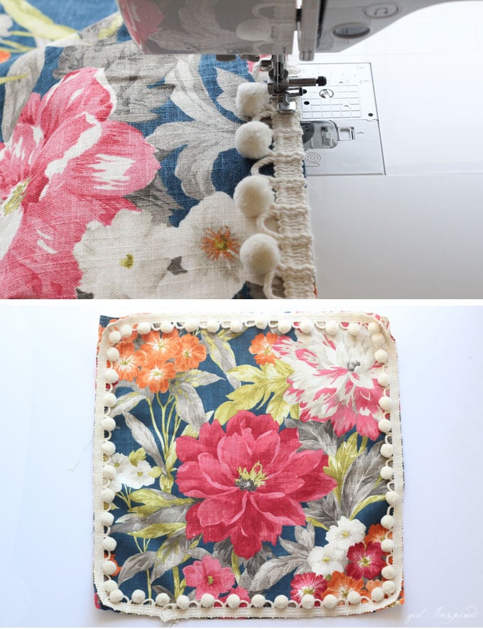 close up of sewing machine stitching pom pom trim onto blue floral fabric and square fabric with trim sewed around perimeter