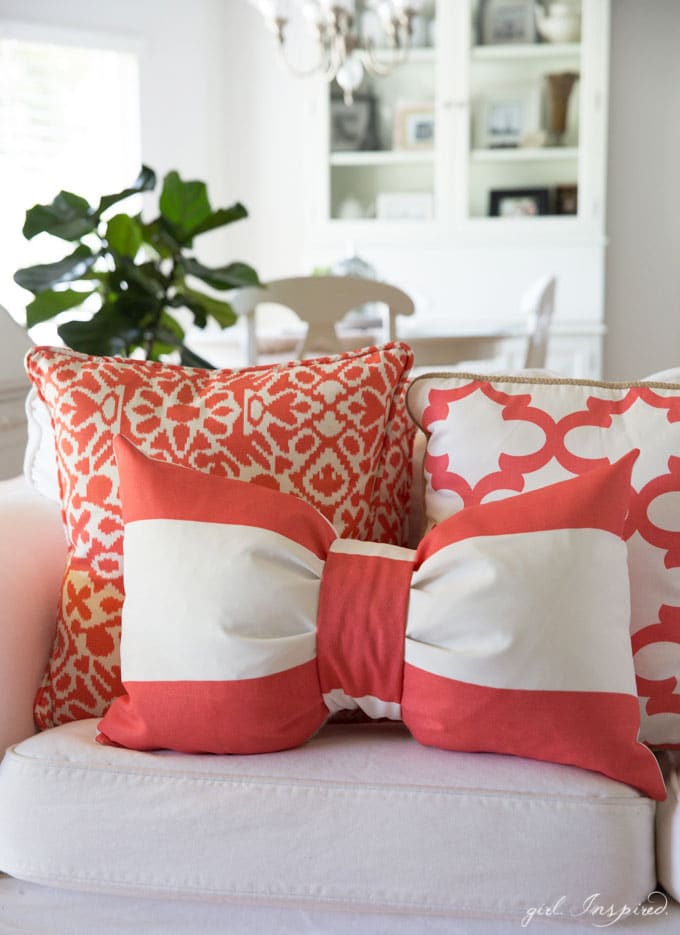 Coral and white bow pillow and coral and white square pillows on white couch