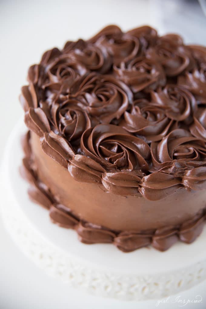 dark chocolate frosting piped in swirls on cake on white platter