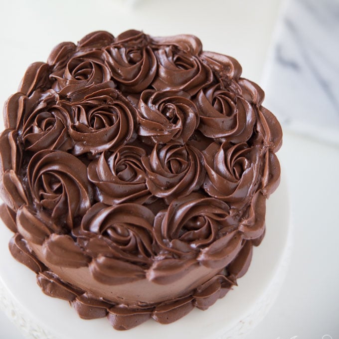dark chocolate frosting piped in swirls on cake on white platter