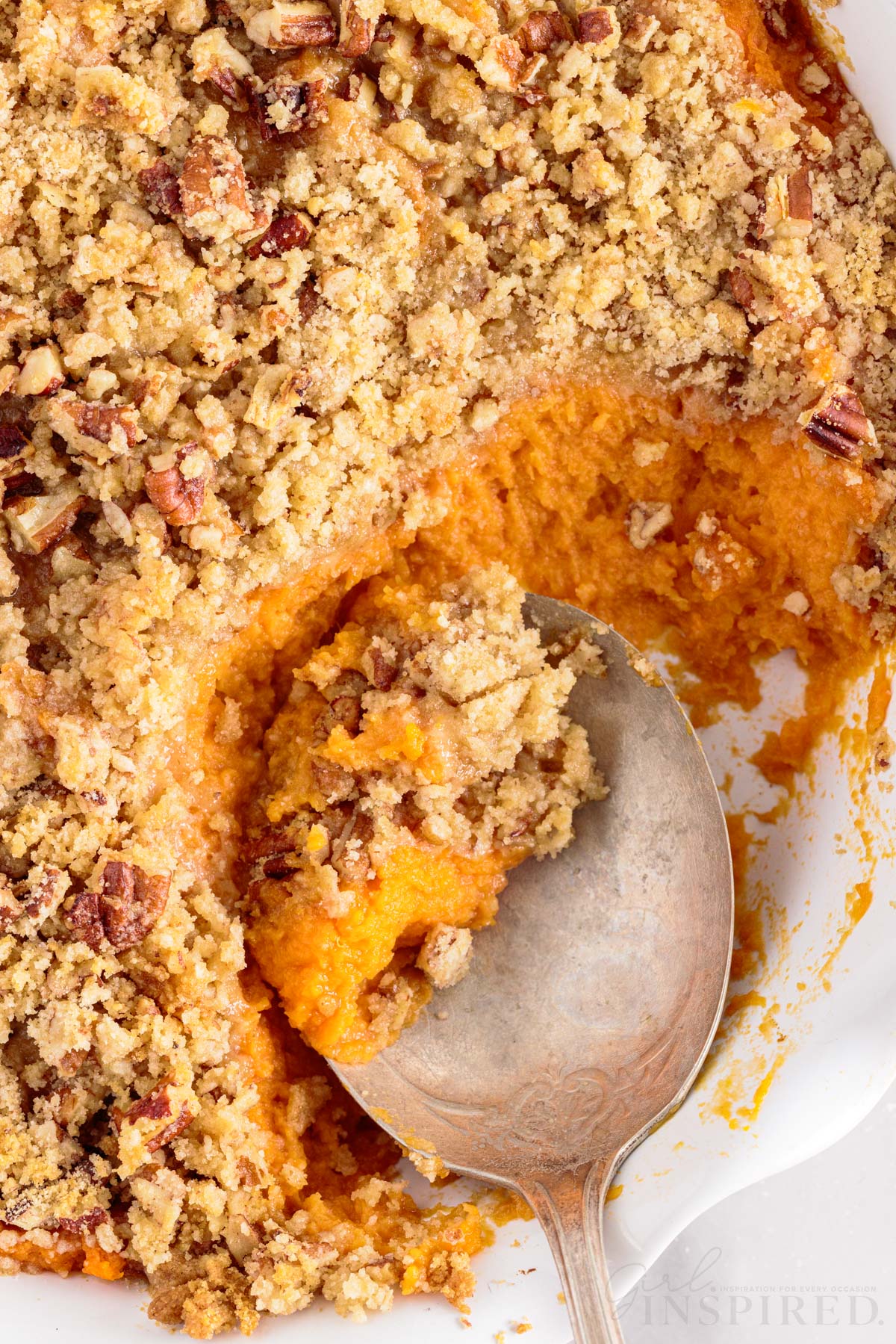 streusel topped sweet potato casserole with scoop removed and spoon in white dish