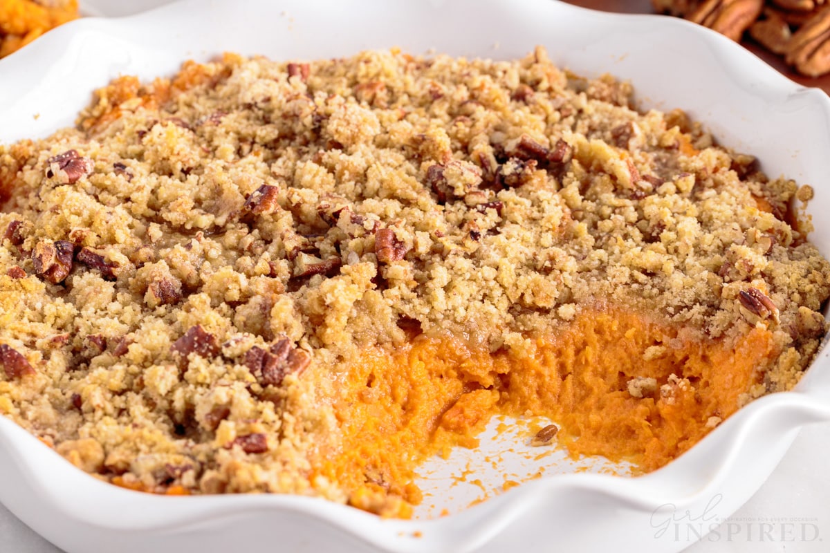side view of pie plate full of sweet potato casserole with a scoop removed.