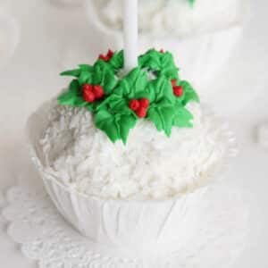 Snowball ice cream with icing wreath around the top and candle in the center, in a paper cup.