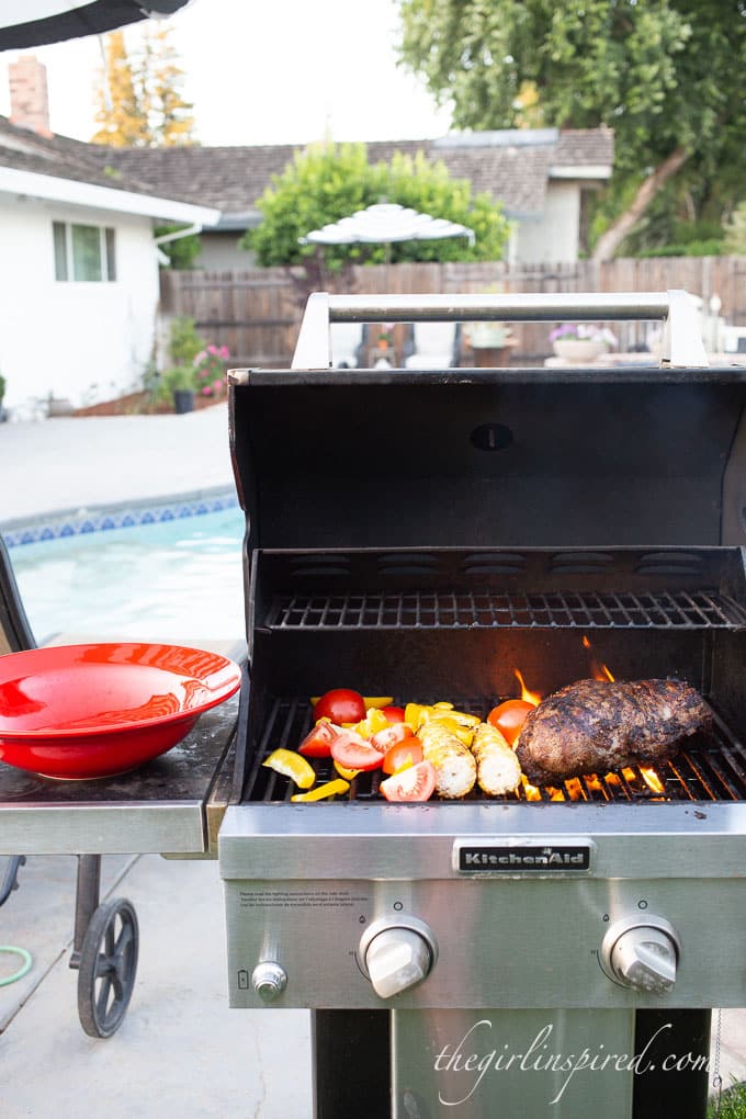 open grill in front of swimming pool with tri tip and vegetables grilling