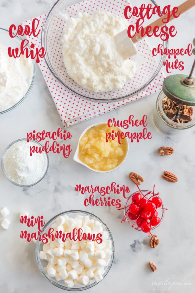 ingredients with text overlay: cottage cheese, chopped nuts, crushed pineapple, mini marshmallows, pudding mix, Cool Whip, and maraschino cherries in individual bowls