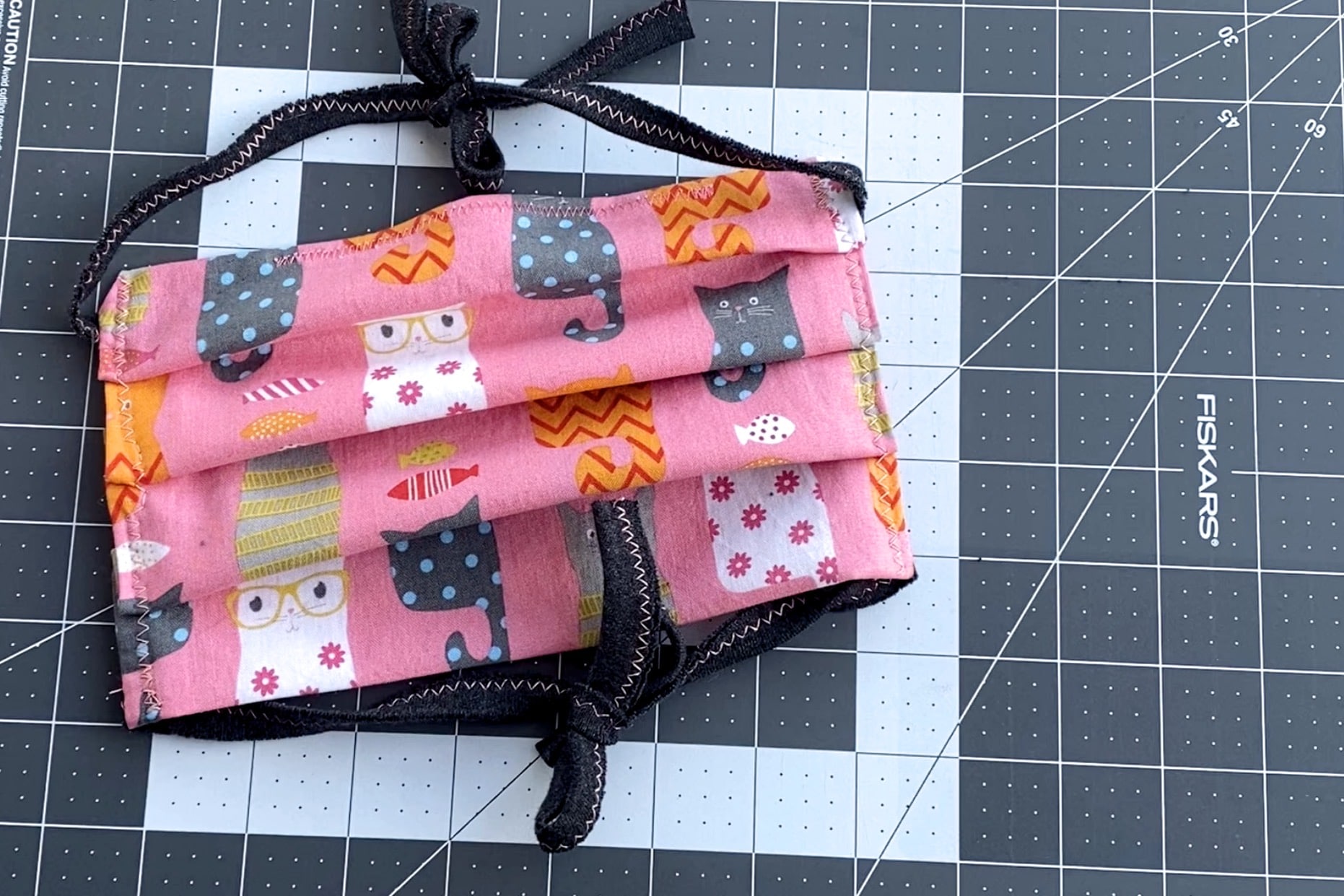 Cat Pattern on pink face mask on grey and white sewing cut mat