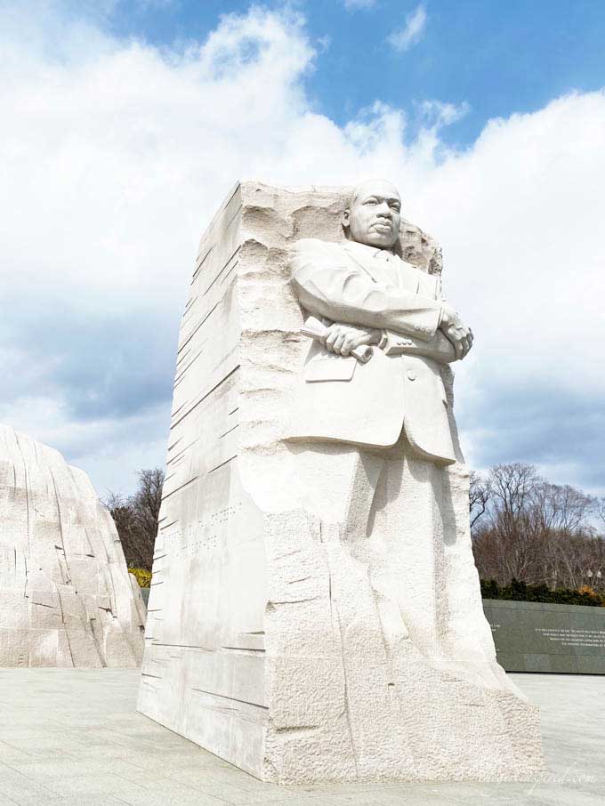 white stone carving of MLK with cloudy blue sky background in DC