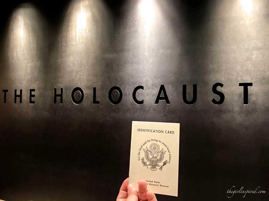 Small white booklet held in front of wall engraved "Holocaust"