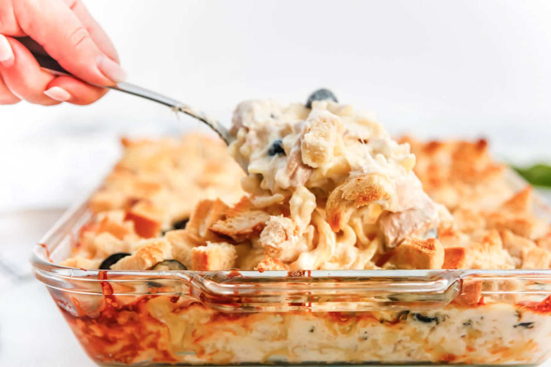 spoonful of baked tuna casserole in glass baking dish