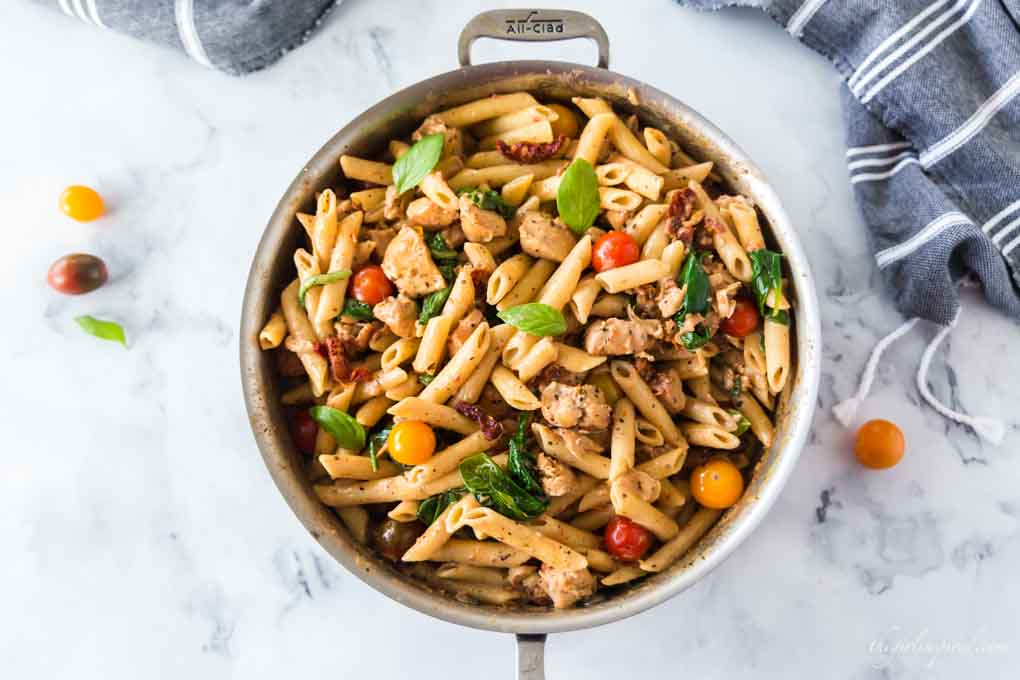 creamy chicken pasta in saucepan with grey dishtowel