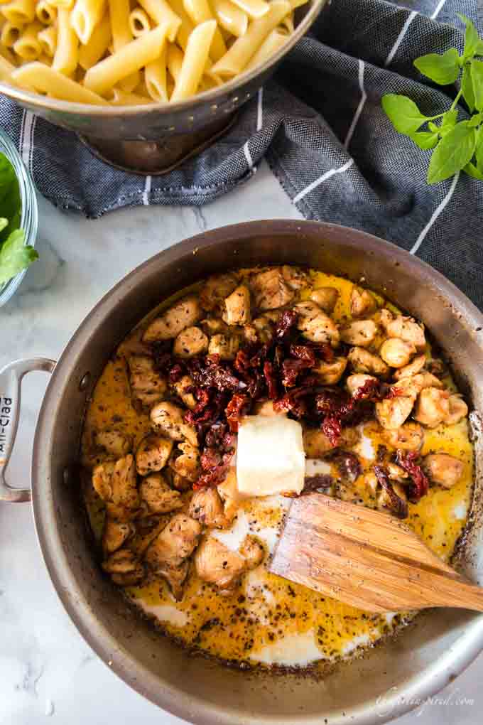 browned chicken in saucepan with sun-dried tomatoes and butter