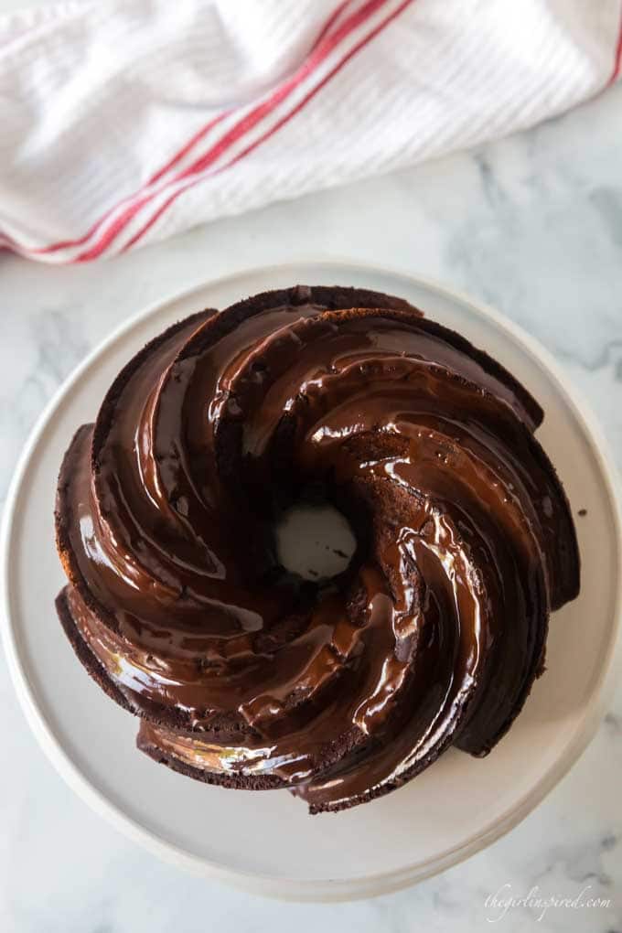 chocolate bundt cake on white cake platter with white and red linen