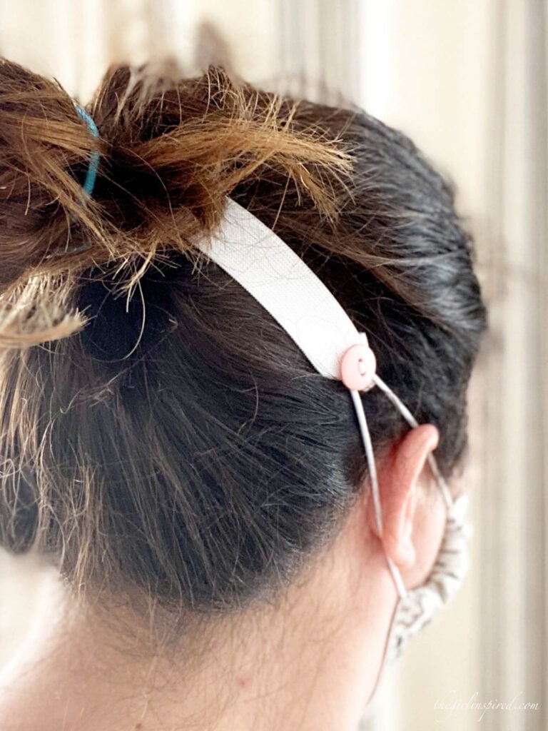 white elastic with pink button across the back of woman's head