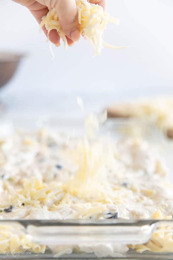 cheese sprinkled over casserole in glass baking dish