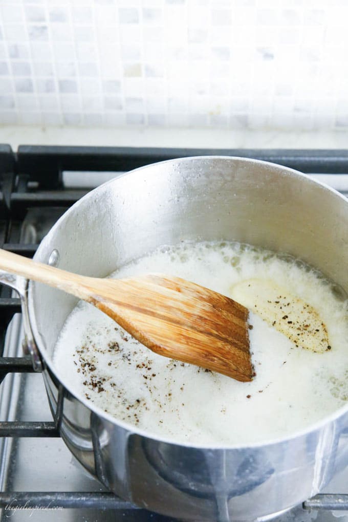 saucepan on stovetop with butter and milk and wooden mixing spoon
