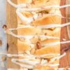 braided sweet bread on cutting board with almonds and icing