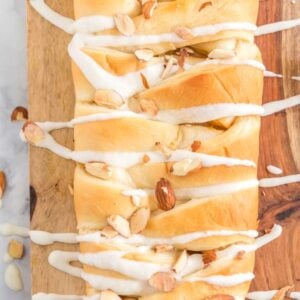 braided sweet bread on cutting board with almonds and icing