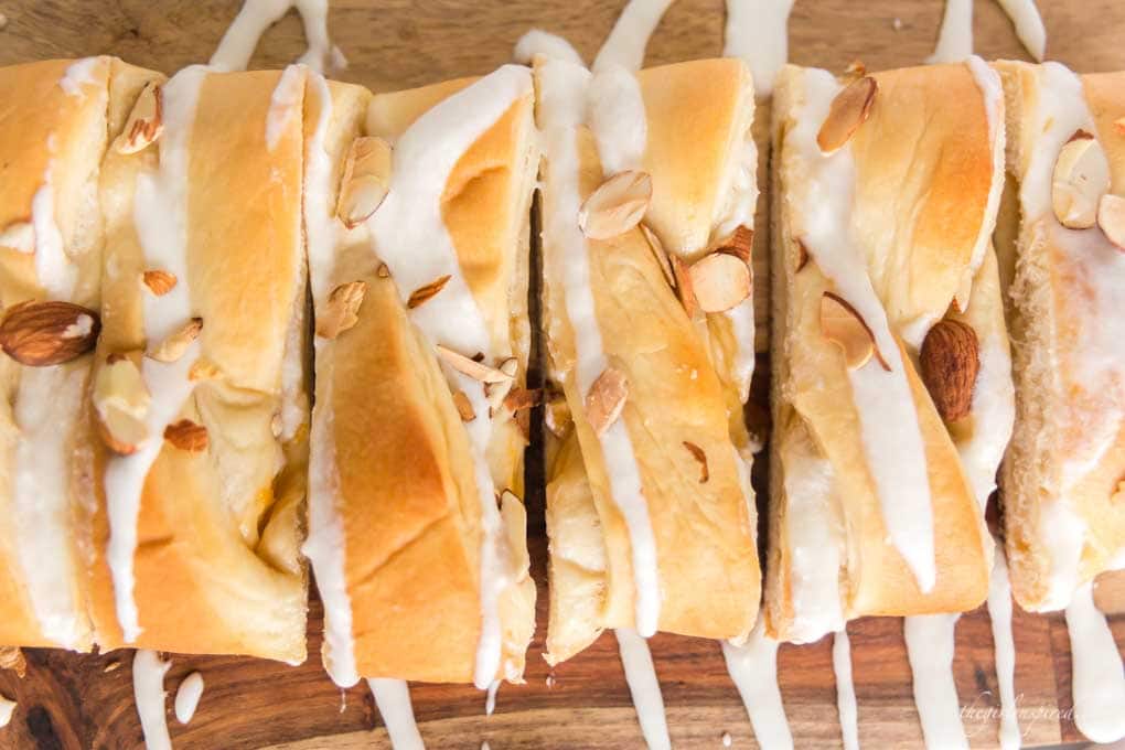 braided sweet bread on cutting board with almonds and icing