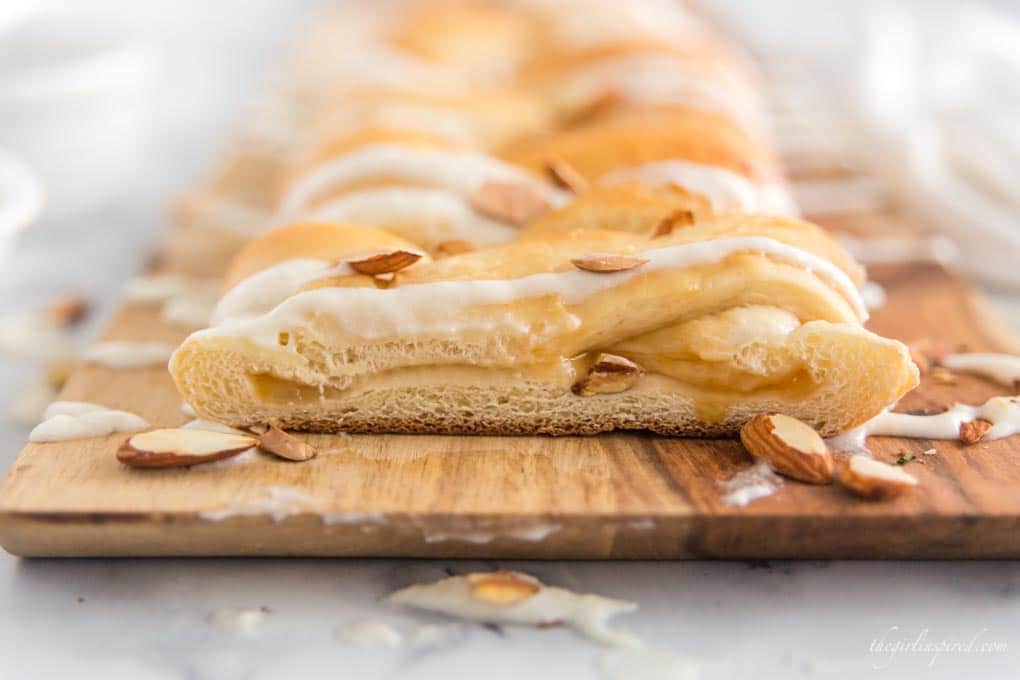 braided sweet bread on cutting board with almonds and icing