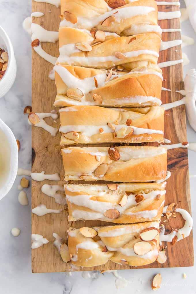 braided sweet bread on cutting board with almonds and icing