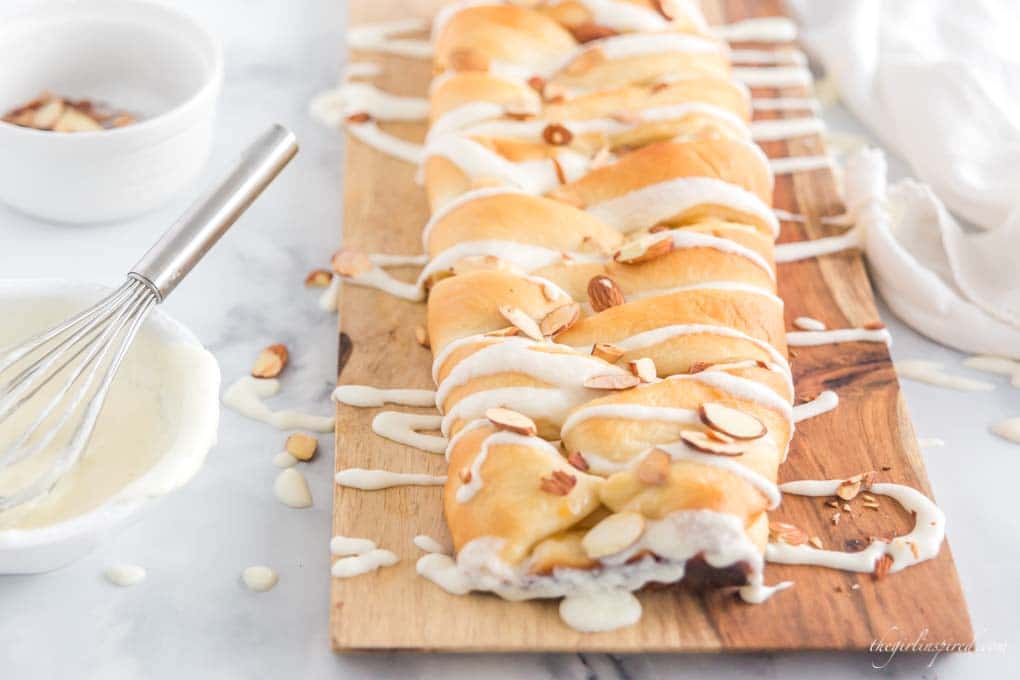 braided sweet bread on cutting board with almonds and icing