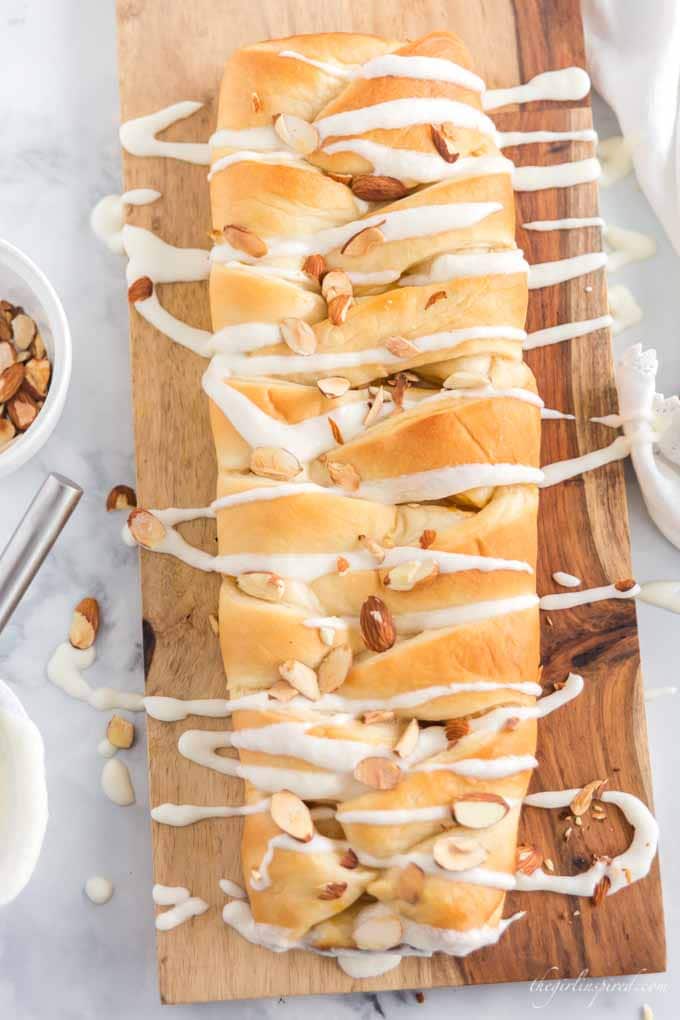 braided sweet bread on cutting board with almonds and icing