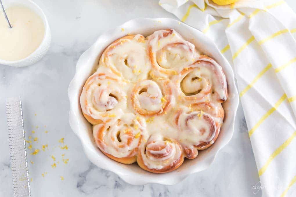 baked sweet rolls in white pie plate, with white dishes, lemons, and dish towel in background