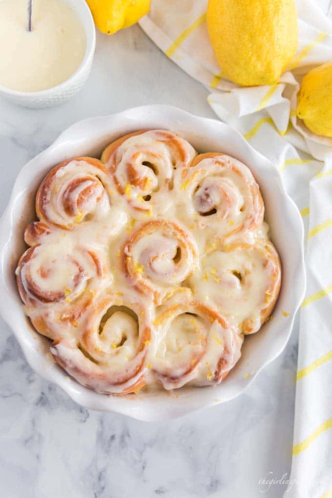 baked sweet rolls in white pie plate, with white dishes, lemons, and dish towel in background