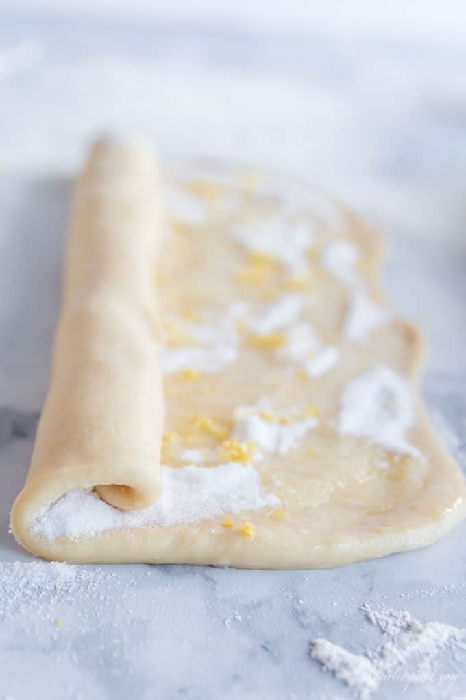 sweet dough with sugar and lemon zest in partially rolled length of dough